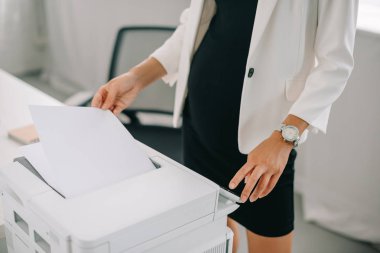 partial view of pregnant businesswoman using printer in office clipart