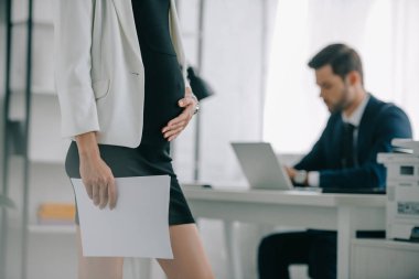 Kısmi belge ve meslektaşım dizüstü bilgisayarda Office işyerinde çalışan hamile işkadını görünümünü