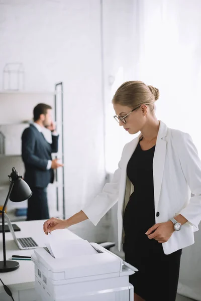 Selective Focus Pregnant Businesswoman Using Printer While Colleague Talking Smartphone — Stock Photo, Image
