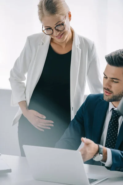 妊娠中の実業家とのオフィスでのプロジェクトについて議論するラップトップで職場の同僚の肖像画 — ストック写真