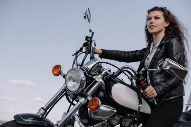 beautiful female biker sitting on vintage motorcycle clipart