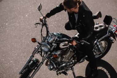 biker sitting on vintage chopper motorcycle on asphalt road clipart