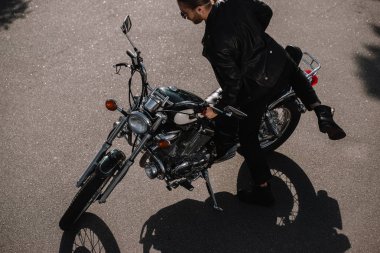 young biker sitting on vintage classical motorcycle on road clipart