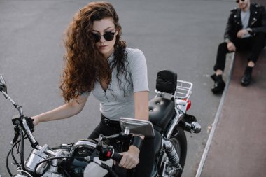 Asfalt yol üzerinde oturan erkek arkadaşı ise klasik Kruvazör motosiklet üzerinde oturan kadın