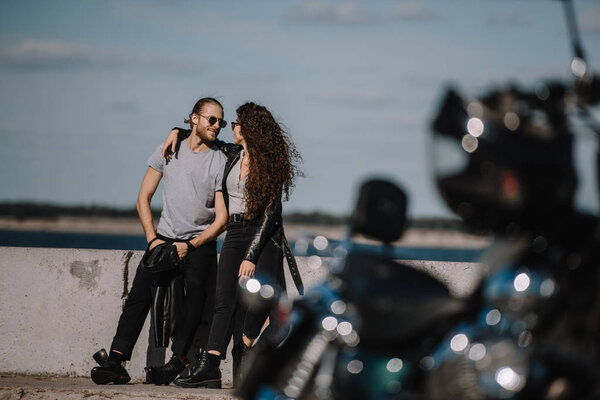 selective focus of young couple hugging on quay with motorcycle on foreground