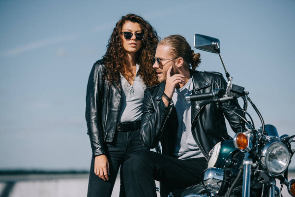 couple of bikers in leather jackets sitting on classical vintage motorcycle