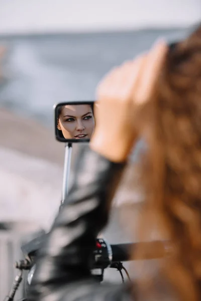 reflection of beautiful woman in mirror of motorcycle