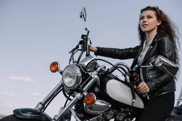 beautiful female biker sitting on vintage motorcycle