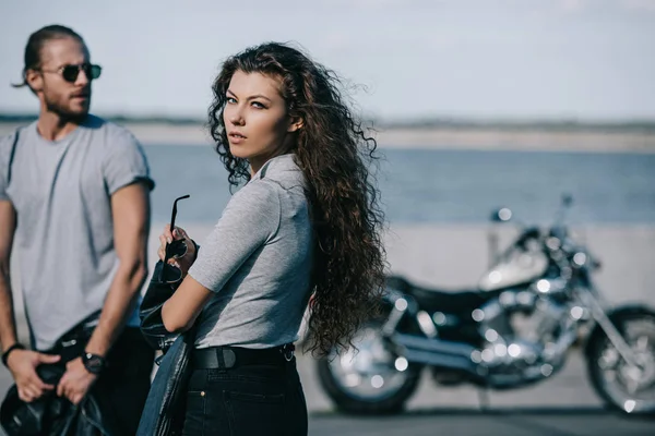 young couple of bikers with vintage motorbike in city