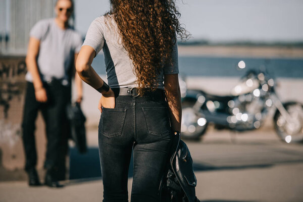 back view of girl going to boyfriend with motorbike 
