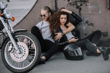 sarılma ve kask ve motosiklet ile asfalt üzerinde oturan bisikletçileri birkaç