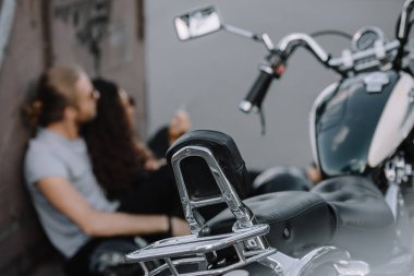vintage motosiklet üzerinde ön plan ile asfalt üzerinde oturan çiftin seçici odak