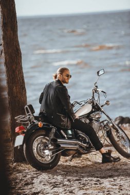 motorcu klasik chopper motosiklet deniz kenarında oturan siyah deri ceketli