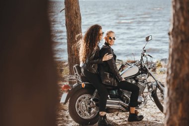 Genç çift bisikletçileri chopper motosiklet sahil üzerinde oturan siyah deri ceket