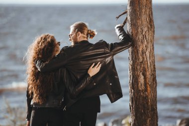 arkadan kaç sarılma ve sahil üzerinde birbirine bakarak siyah deri ceket içinde görünüşü