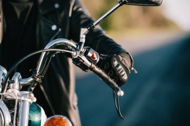 cropped view of biker sitting on classic motorcycle clipart