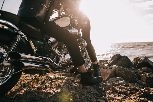 cropped view of couple on chopper motorbike near sea with sunlight