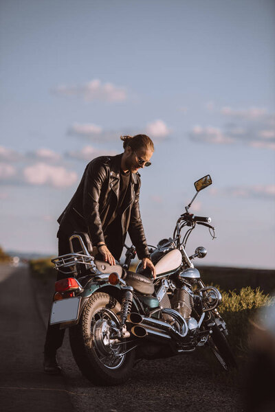 handsome male biker with classical motorcycle on road