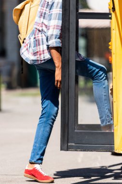 cropped shot of african american schoolboy entering school bus clipart