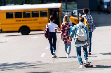 okul otobüsü park tarafından yürüyüş genç bilim adamlarının grubunun arka görünüm