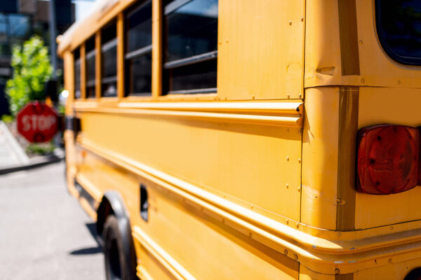 partial view of traditional school bus with stop sign