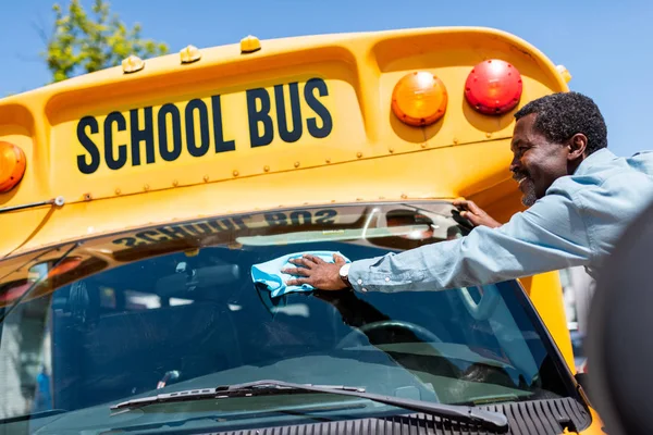 Щасливий Зрілий Афроамериканський Водій Автобуса Стирає Переднє Вікно Шкільного Автобуса — стокове фото