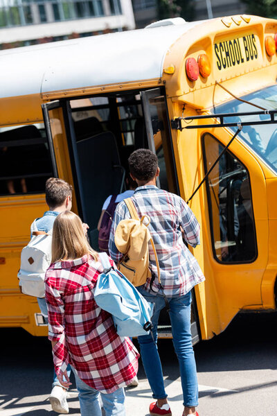 rear view of group of students walking into school bus