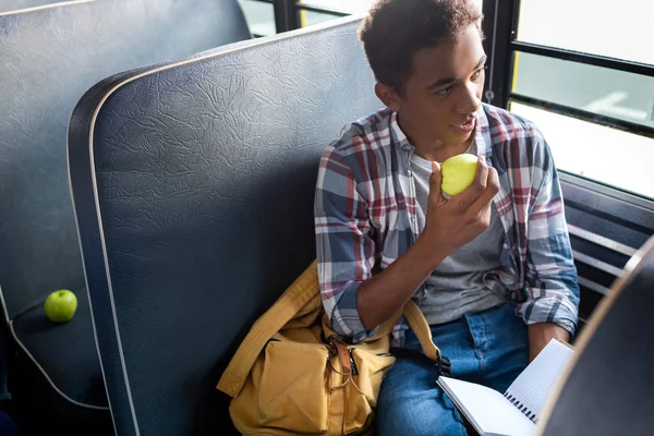 Adolescente Africano Americano Escolar Lectura Manzana Mientras Celebración Blanco Notebook —  Fotos de Stock