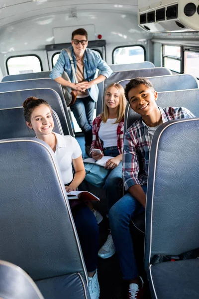 Grupa Uczonych Uśmiechający Się Nastolatka Jazda Autobusem Szkolnym Patrząc Kamery — Zdjęcie stockowe