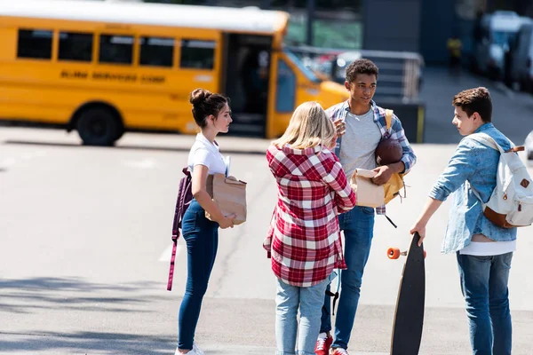 学校のバスの前に駐車場でチャット 代の学者のグループ — ストック写真