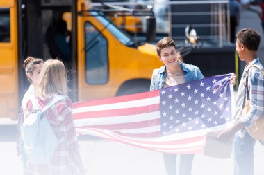 Amerika Birleşik Devletleri bayrağı önünde okul otobüsü ile Amerikan genç bilim adamlarının Grup
