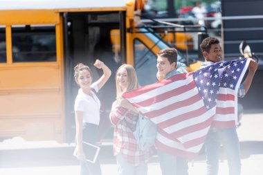 ABD bayrağı önünde okul otobüsü ile mutlu Amerikan genç bilim adamlarının Grup