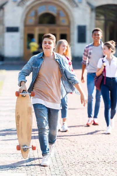 Χαμογελώντας Έφηβος Μαθητής Skateboard Περπάτημα Φίλους Μετά Σχολείο — Δωρεάν Φωτογραφία