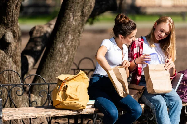 Glücklich Teen Schoolgirls Sitzen Auf Bank Während Des Mittagessens — Stockfoto