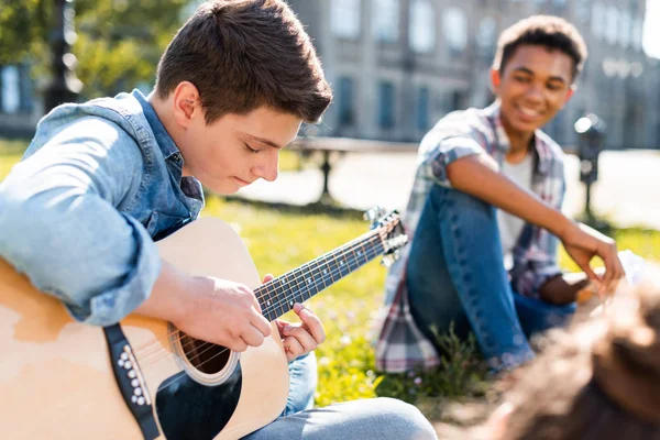 Adolescents Heureux Assis Sur Herbe Jouer Guitare Acoustique — Photo