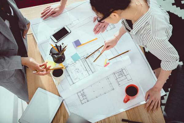 Cropped shot of professional young architects working with blueprint 