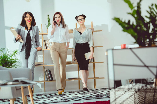 young smiling multiethnic businesswomen walking together at office