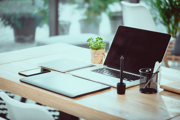 ноутбук с чистым экраном и графический планшет со смартфоном на деревянном столе в офисе
