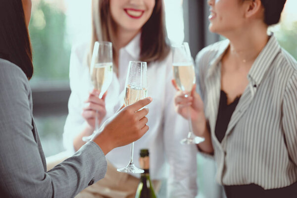 cropped shot of businesswomen in formal wear drinking champagne indoors