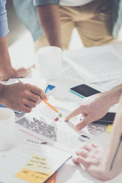 частичное представление крупным планом бизнесменов, указывающих на диаграммы и работающих над новым проектом в офисе
 