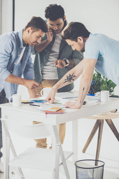 ориентированные молодые многонациональные бизнесмены, работающие над новым проектом в офисе
