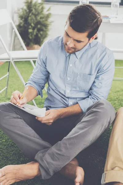 Jonge Barefoot Zakenman Zitten Met Potlood Papier Schrijft — Stockfoto