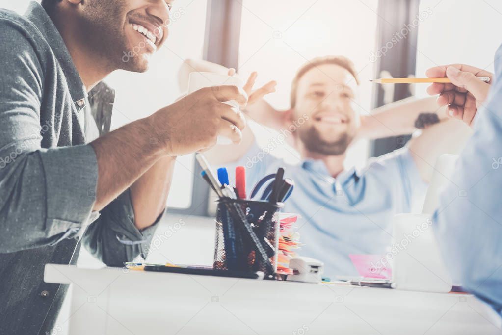 cropped shot of smiling young multiethnic businessmen working on new project at office, business teamwork concept