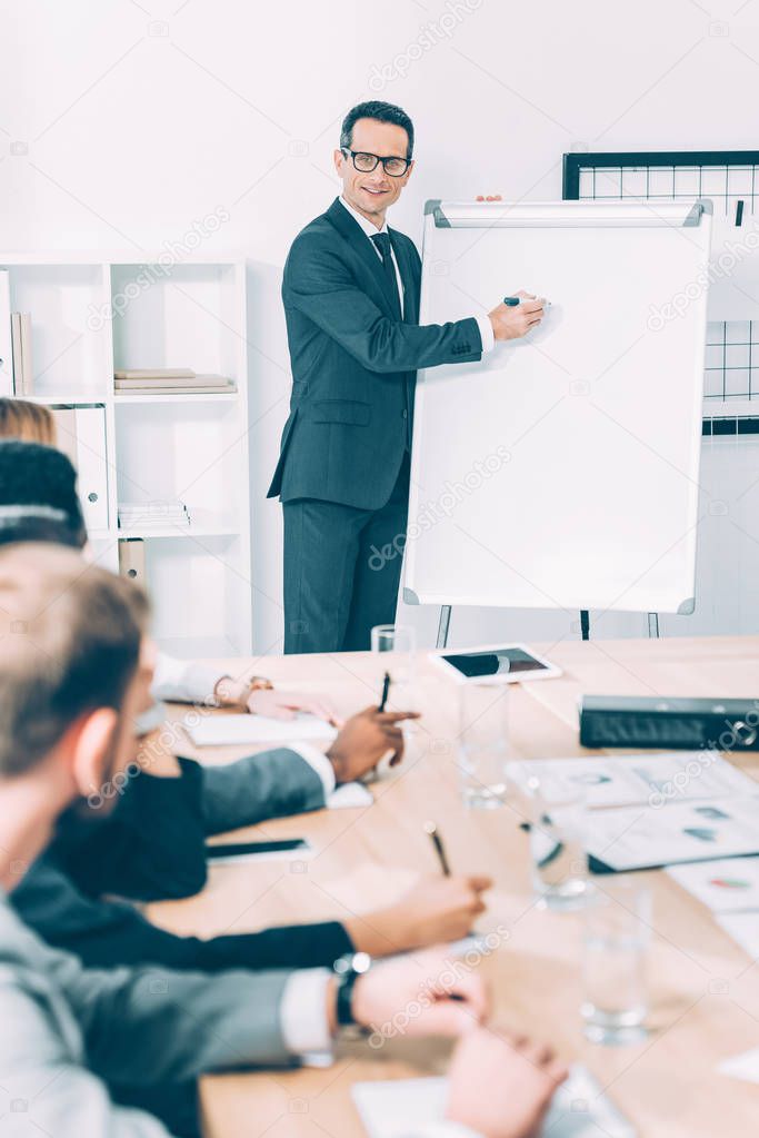 smiling mature businessman giving presentation at conference hall