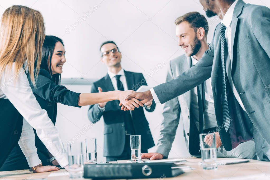 multicultural businesspeople shaking hands in conference hall