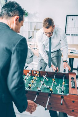 modern ofis masa futbolu oynayan yakışıklı iş adamları