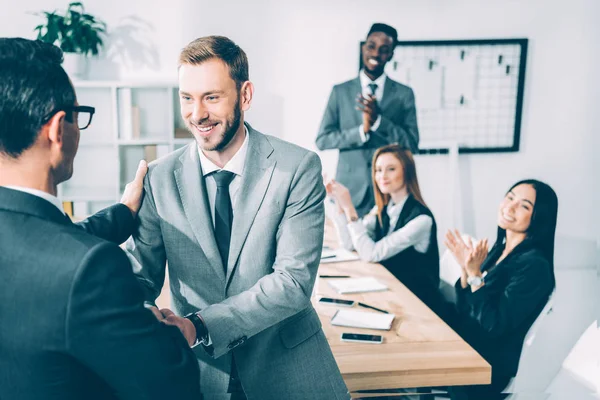 Empresarios Estrechando Mano Sala Conferencias Con Socios Multiculturales Sentados Mesa — Foto de Stock