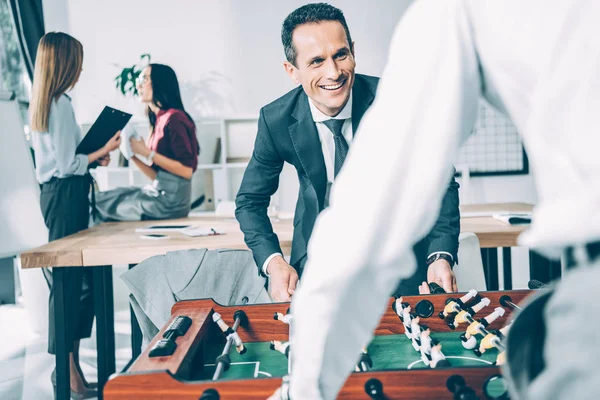 Geschäftsleute Spielen Tischkicker Modernen Büro Während Geschäftsfrauen Hintergrund Verschwommen Reden — Stockfoto