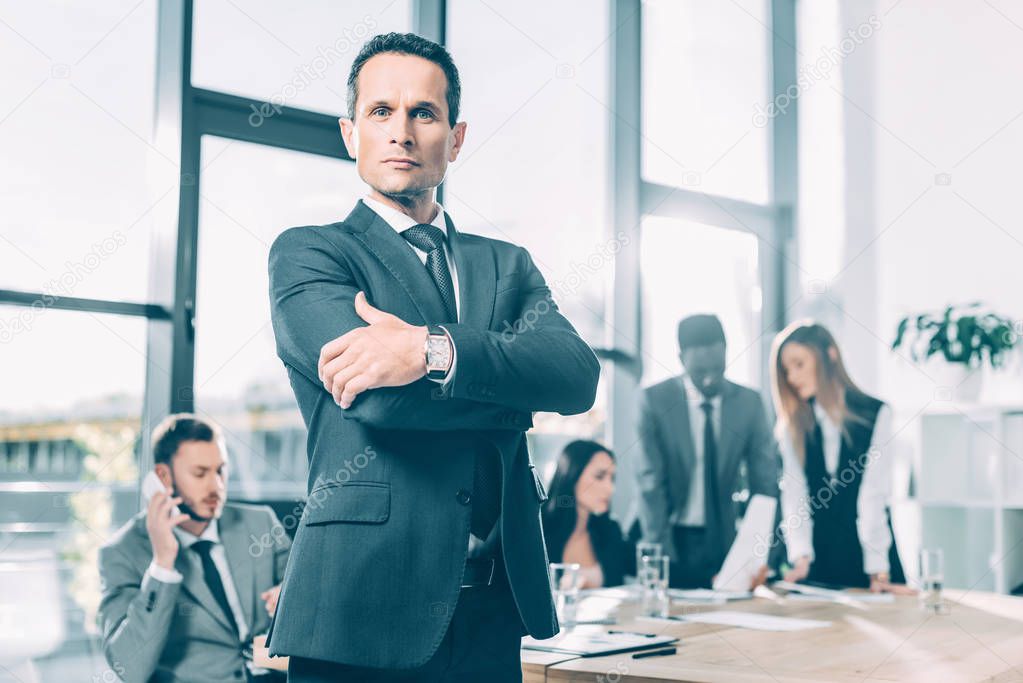 handsome businessman looking at camera with crossed arms in conference hall