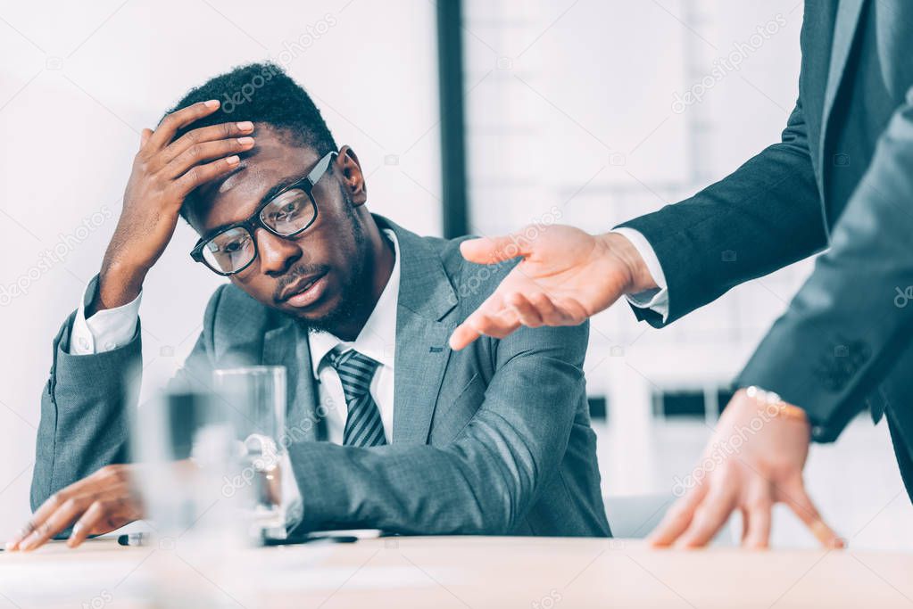 partial view of exhausted african american businessman listening to boss